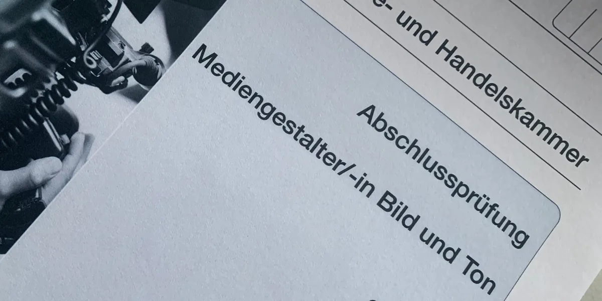 Prüfungsunterlagen zur Abschlussprüfung Mediengestalter/in Bild und Ton neben einer Kamera